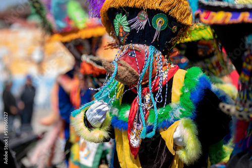 A person with a colorful chinelo costume, dancing in a carnival in Mexico