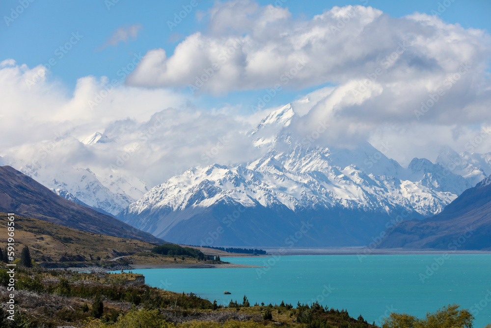 The magnificent, snow-covered Aoroki or Mount Cook, the highest mountain in New Zealand, is seen from an azure Lake Pukaki