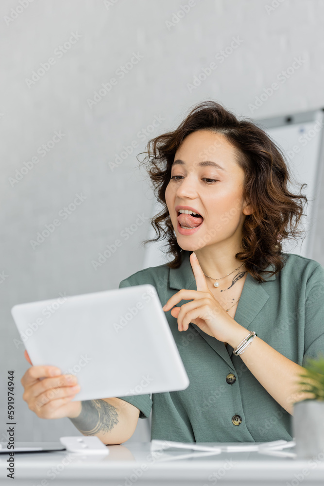 Speech therapist pointing at tongue during online lesson in consulting room. Speech therapist pointing at tongue during online lesson in consulting room.