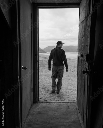 A man and the Valley of Ten Thousand Smokes is framed by the doorway of one of the Baked Mountain Huts in Katmai National Park; Alaska, United States of America