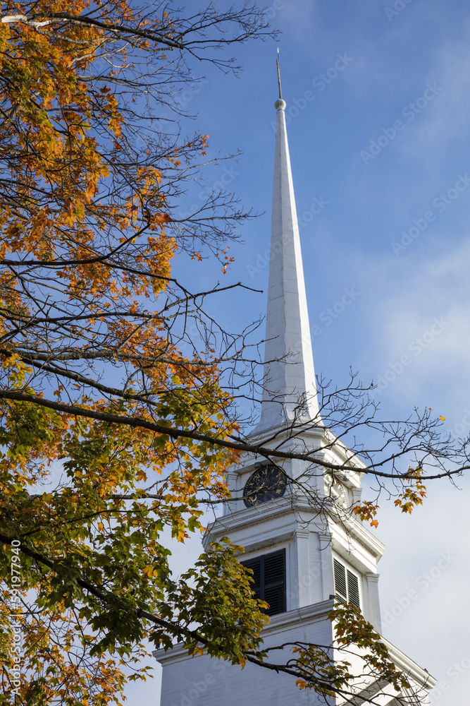 Stowe Church in Vermont with a tall white steeple and clock and tree foliage in autumn colours; Stowe, Vermont, United States of America Stowe Church in Vermont with a tall white steeple and clock and tree foliage in autumn colours; Stowe, Vermont, United States of America
