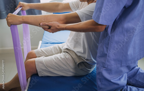 Doctor or Physiotherapist working examining treating injured arm of athlete male patient, stretching and exercise, Doing the Rehabilitation therapy pain in clinic.