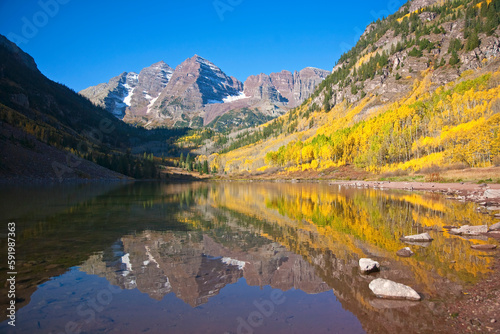 Maroon Bells during fall, with the aspen (Populus tremuloides) leaves changing color reflected in a calm lake; Maroon Creek Valley, Aspen, Colorado, United States of America photo