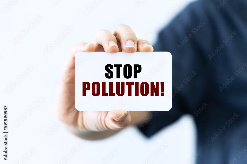 Stop pollution text on blank business card being held by a woman's hand with blurred background. Business concept about stopping pollution. Stop pollution text on blank business card being held by a woman's hand with blurred background. Business concept about stopping pollution.