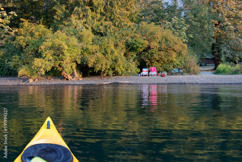 Kayaking on Cultus Lake with a view of chairs sitting on the shore at the water's edge in Cultus Lake Provincial Park; Cultus Lake, British Columbia, Canada photo