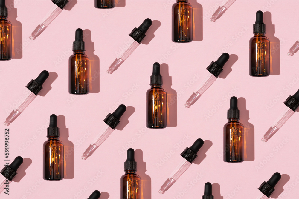 Simple face skincare pattern made with dark brown glass serum or essential oil bottle and dropper on pastel pink background. Minimal fresh product aesthetic. Simple face skincare pattern made with dark brown glass serum or essential oil bottle and dropper on pastel pink background. Minimal fresh product aesthetic.