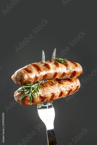 Barbecue sausages with rosemary on a fork. meat sausages in skins with spices, vertical image. place for text