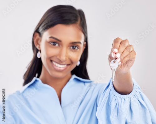 Happy  showing and a portrait of a woman with keys isolated on a white background in a studio. Real estate  smile and a girl holding a key to a house  apartment or property as a new homeowner