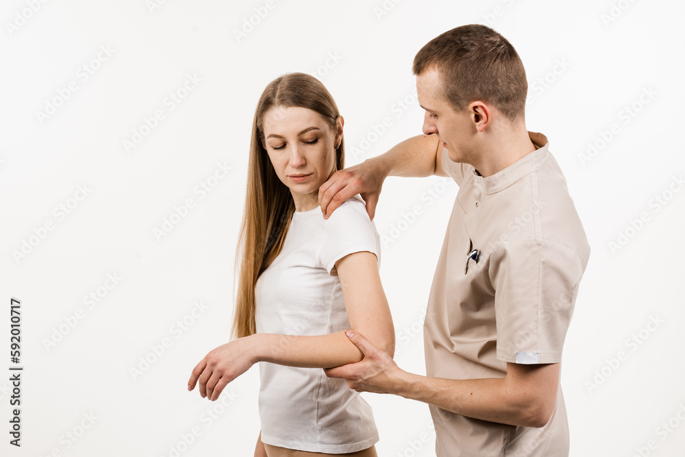 Movement assessment or shoulder joint mobilization. Muscle release. Orthopedic traumatologist examines shoulder joint of patient and checks mobility of movements on white background. Movement assessment or shoulder joint mobilization. Muscle release. Orthopedic traumatologist examines shoulder joint of patient and checks mobility of movements on white background.