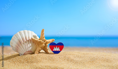 Tropical beach with seashells and Cambodia flag. The concept of a paradise vacation on the beaches of Vietnam.