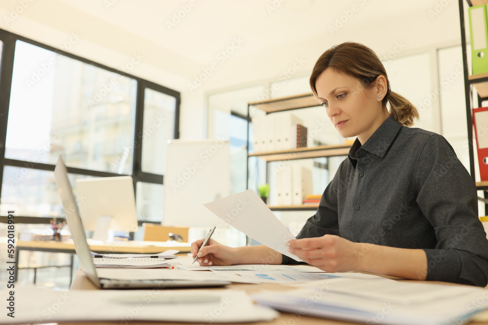 Woman with ponytail checks information making notes on paper Woman with ponytail checks information making notes on paper