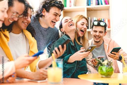 Group of happy students having fun using mobile phone and sharing social content- Young millenial friends watching smartphone at university classroom-Life style Internet Technology concept  photo