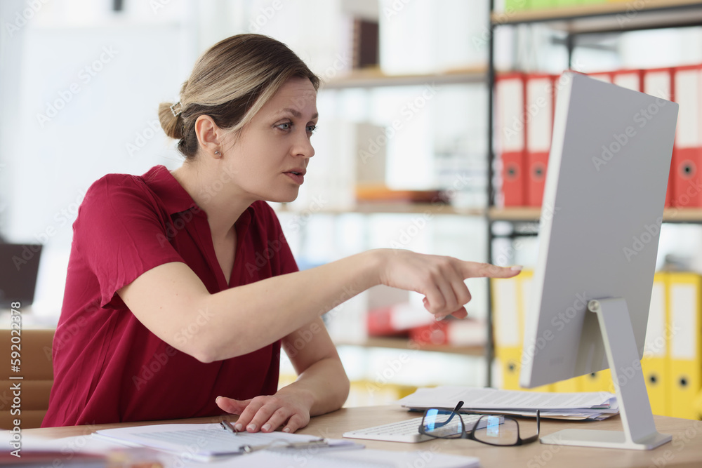 Suspicious woman points finger to screen of computer monitor Suspicious woman points finger to screen of computer monitor