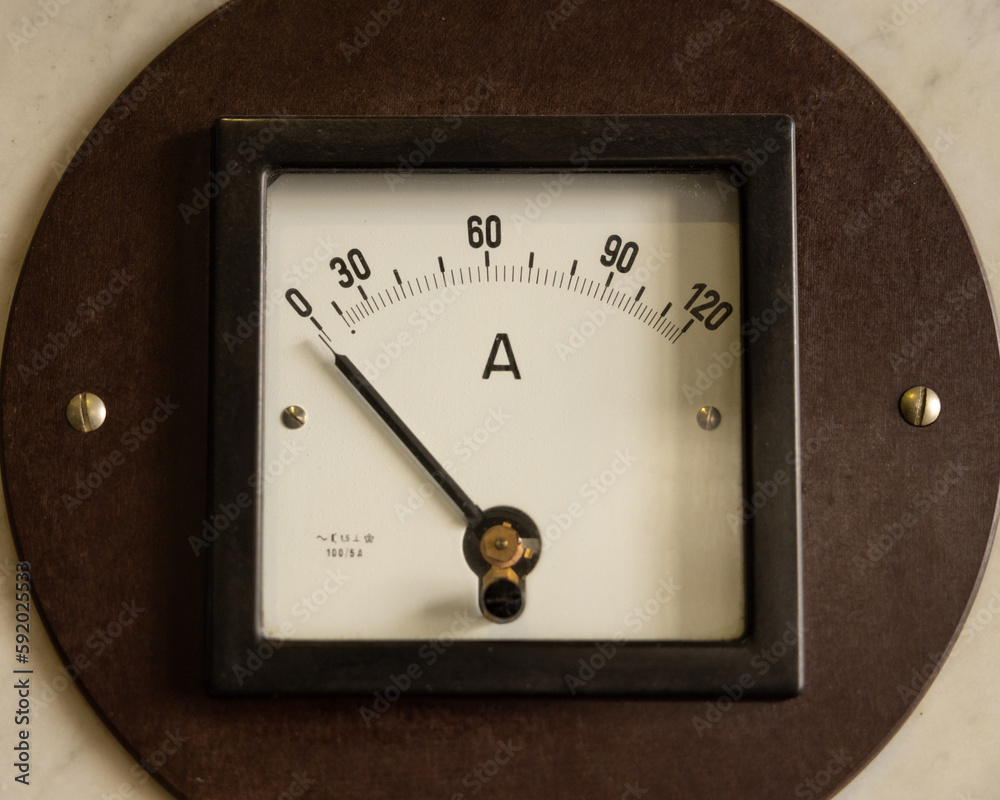 An antique non-working ammeter in a wooden frame hangs on the wall An antique non-working ammeter in a wooden frame hangs on the wall