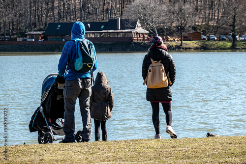 A family on an afternoon walk by the lake in winter