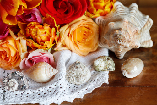 A sea shells on the table and flowers in the background.