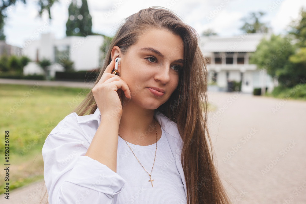 Relaxed young woman brunette in wireless headphones walk on the street listening to music. Enjoying listening to lounge music live via smartphone app, relaxed, eyes closed, laughing, touch earphones. Relaxed young woman brunette in wireless headphones walk on the street listening to music. Enjoying listening to lounge music live via smartphone app, relaxed, eyes closed, laughing, touch earphones.