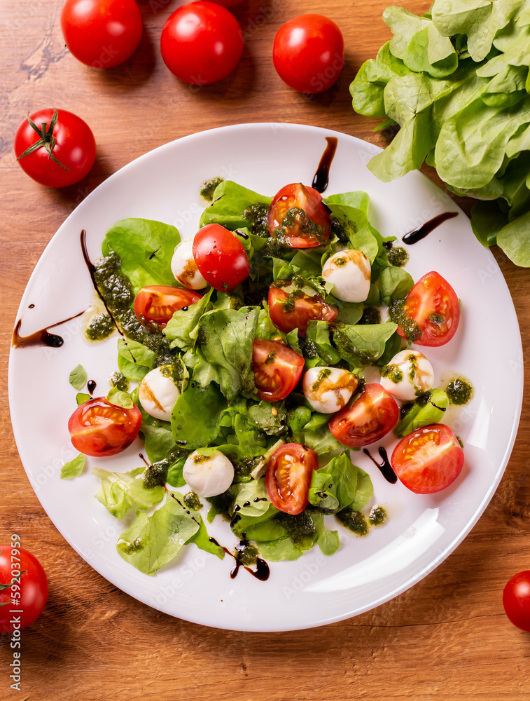 Plate of healthy classic top view caprese salad with mozzarella cheese tomatoes and basil in kitchen - italian cuisine top view Plate of healthy classic top view caprese salad with mozzarella cheese tomatoes and basil in kitchen - italian cuisine top view