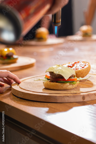 Preparing delicious burgers. Chef cooking meat burgers with beef, cheese and vegetables. Close-up