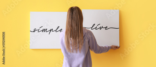 Young woman hanging picture...
