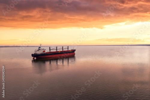 Cargo ship in the open sea at the beautiful sunset. Aerial top view.Shipping. Grain export