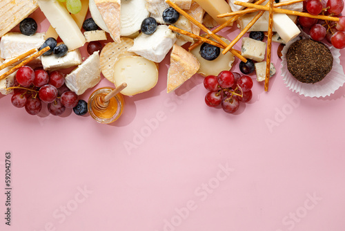 Cheese banner, assortment of traditional cheese, brie, gorgonzola, lambert, livaro, raclette. Antipasto, corner border, copy space. Pink background, top view.