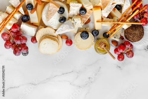 Cheese banner, assortment of traditional cheese, brie, gorgonzola, lambert, livaro, raclette. Antipasto, corner border, copy space. Marble white background, top view.