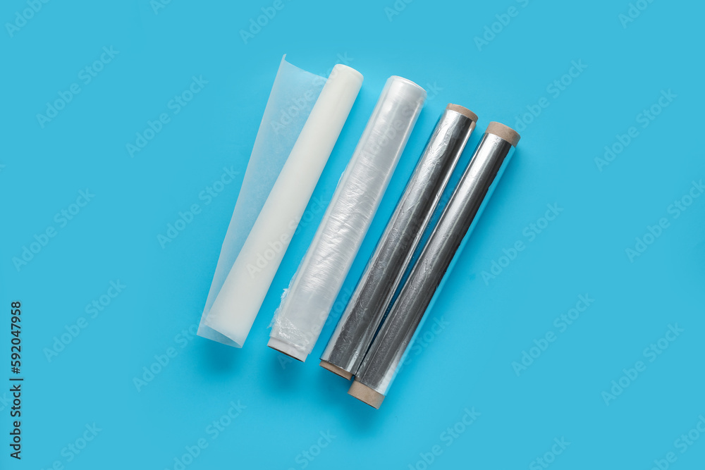 Rolls of aluminium foil, food film and baking paper on color background Rolls of aluminium foil, food film and baking paper on color background
