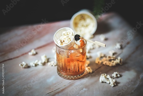 Angled Side View of Old Fashioned with Popcorn Garnish: Unique Twist, Whiskey Delight, Amber Color, Icy Refreshment, Creative Mixology, Playful Touch, Sophisticated Drink