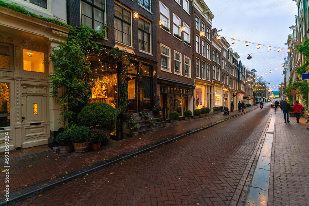 Narrow street with shops at the old town by sunset in Amsterdam, the netherlands