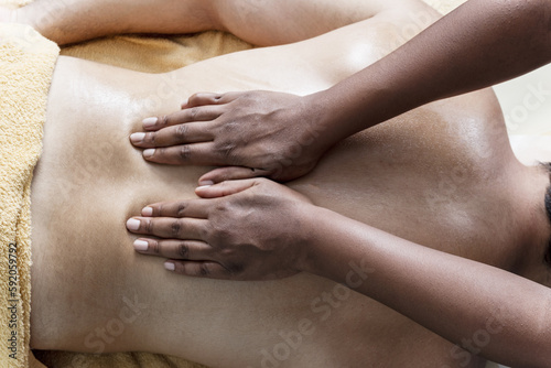 Hands of a brunette masseuse applying pressure on the back of a patient in a beauty clinic