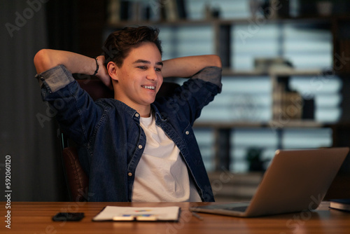 Excited young guy entrepreneur looking at laptop screen, smiling