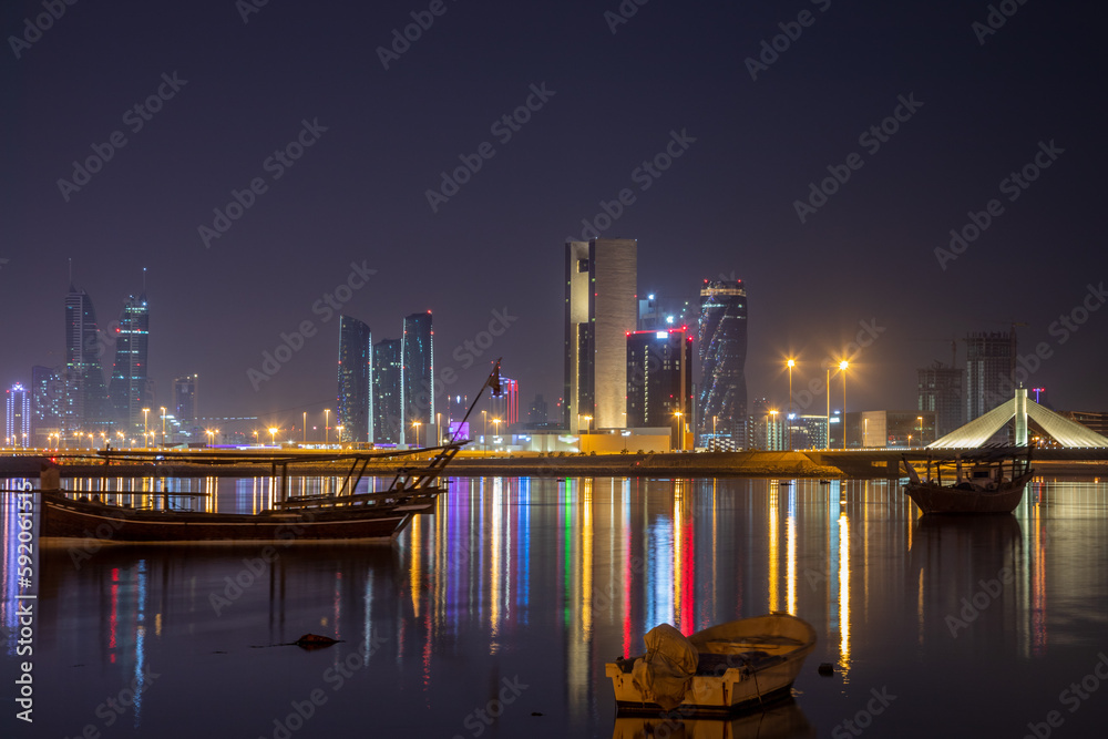Motor boats on the shore of Persian Gulf with illuminated downtown in the background, Manama, Bahrain