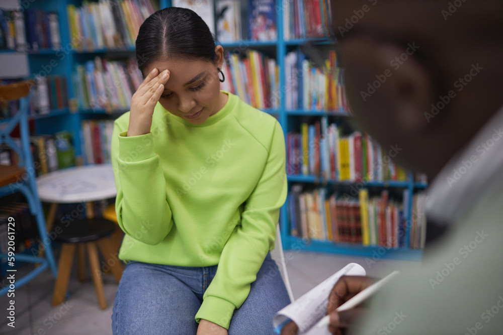 Portrait of stressed young woman hiding face in therapy session with male psychologist in college Portrait of stressed young woman hiding face in therapy session with male psychologist in college