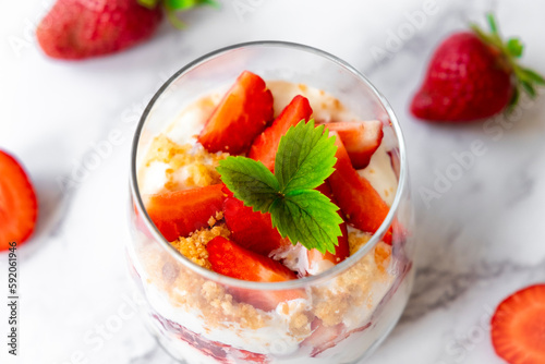 Canvas Print Strawberry trifle dessert with custard, cake crumb and fresh strawberry in glass on marble