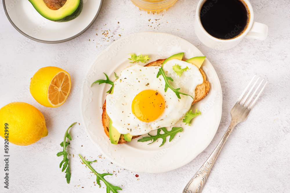 Delicious sandwich with fried egg, arugula and avocado on light background Delicious sandwich with fried egg, arugula and avocado on light background