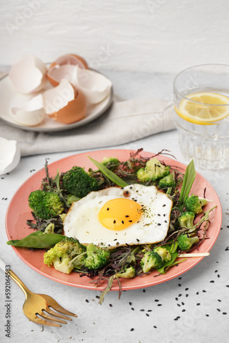 Plate with tasty fried egg and salad on table