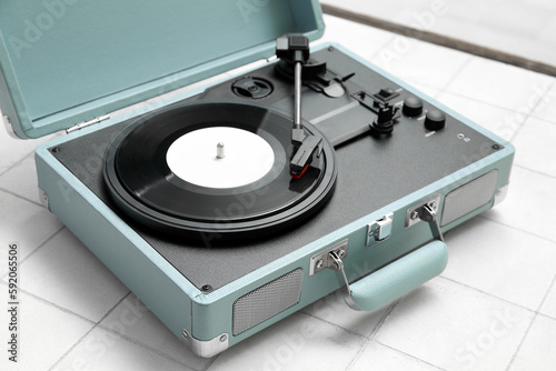 Record player with vinyl disk on white tile background, closeup