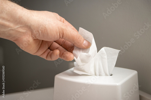 Hand pulling facial tissue from dispenser photo