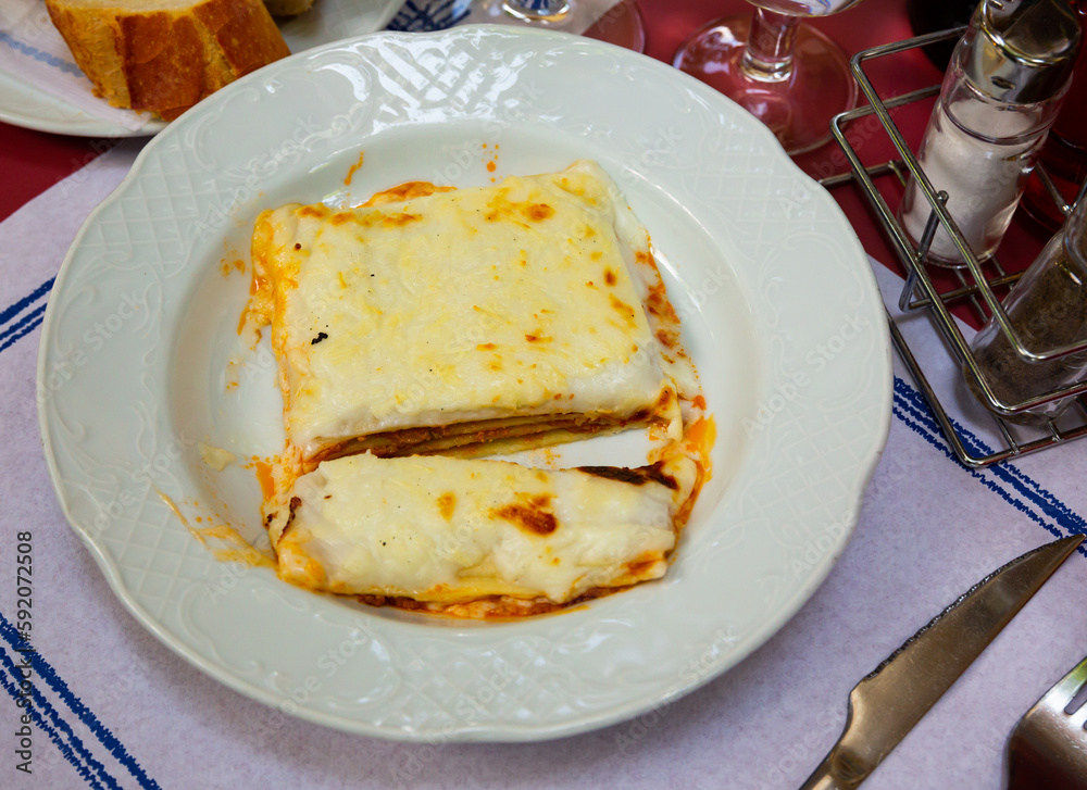 Fresh portion of Italian cuisine dish lasagna served on circular plate.