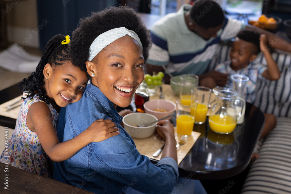 High angle portrait of cheerful african american mother and daughter sitting at dining table at home High angle portrait of cheerful african american mother and daughter sitting at dining table at home
