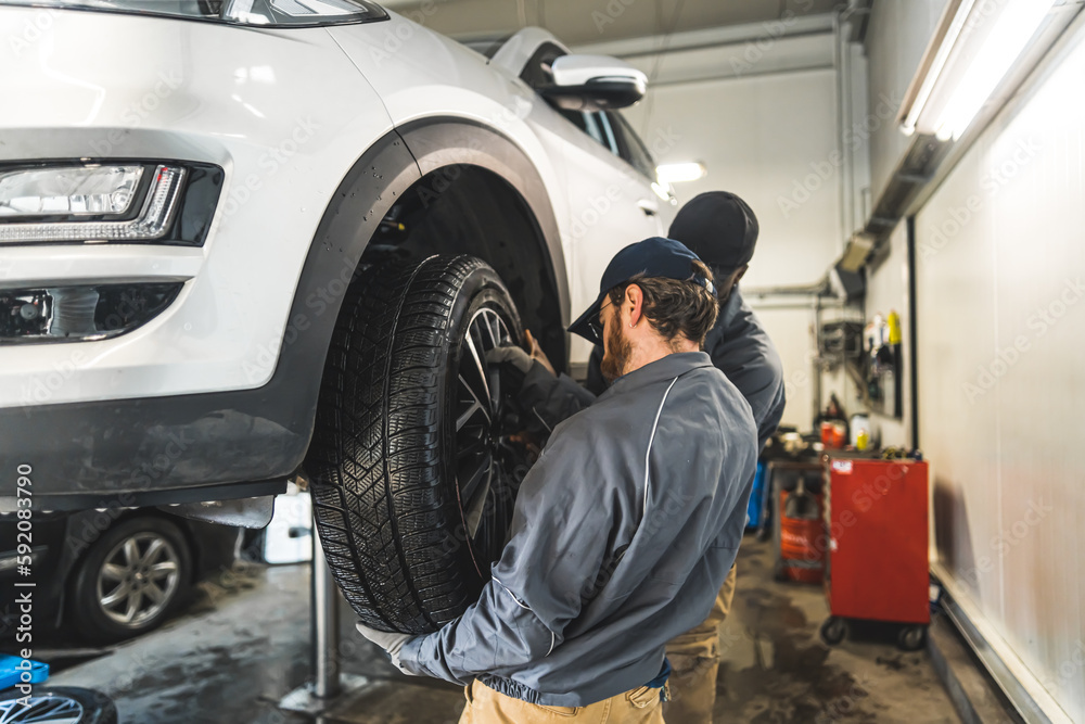 car wheel changing process in the garage, two mechanics working in the workshop. High quality photo car wheel changing process in the garage, two mechanics working in the workshop. High quality photo