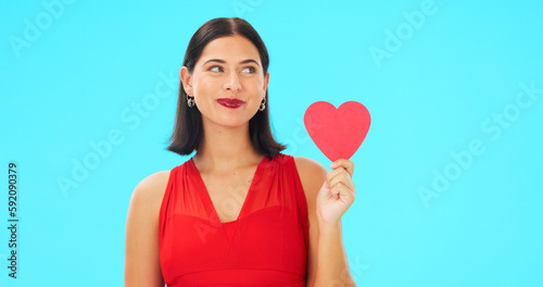 Paper heart, happy woman and face on blue background, studio and backdrop. Portrait of female model in red dress with shape of love, trust and romance for valentines day, flirting and elegant smile