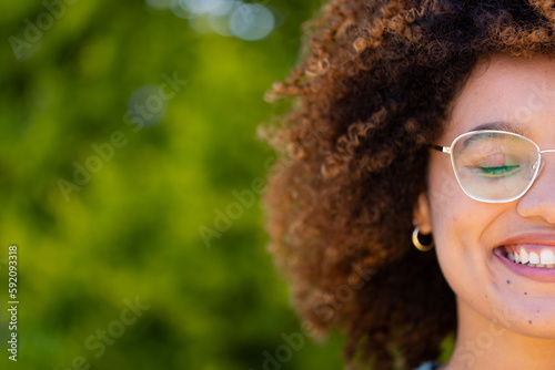 Cropped face of biracial young woman with eyes closed and afro hair smiling in yard photo
