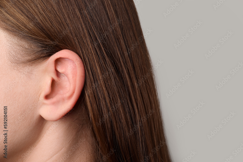 Closeup view of woman against light grey background, focus on ear Closeup view of woman against light grey background, focus on ear