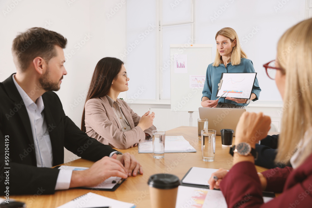 Businesswoman showing chart on meeting in office Businesswoman showing chart on meeting in office