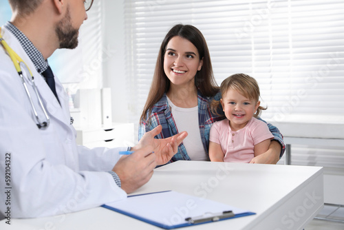 Mother and her cute baby having appointment with pediatrician in clinic. Doctor examining little girl