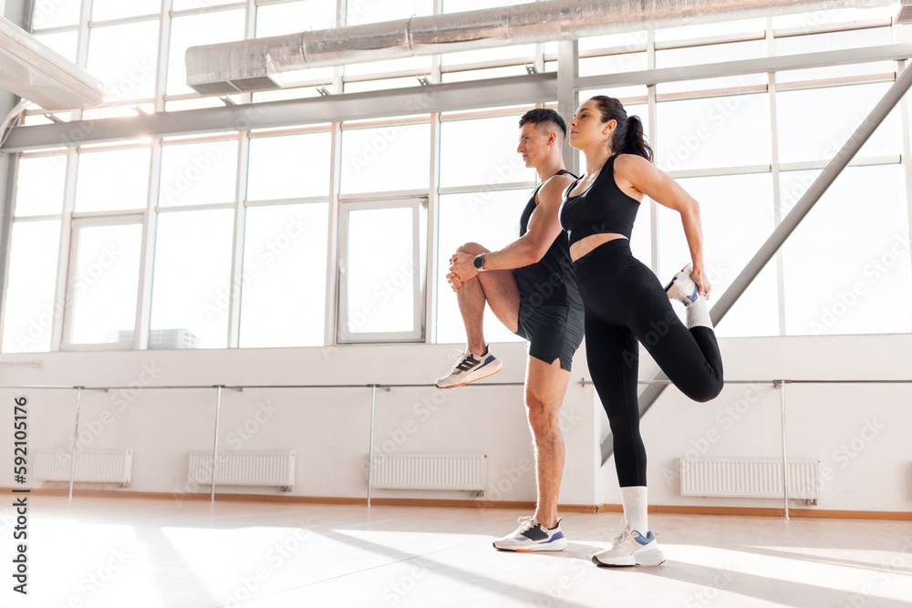 athletic couple in sportswear warm up in the gym in the morning, fitness girl and coach man go in for sports in training athletic couple in sportswear warm up in the gym in the morning, fitness girl and coach man go in for sports in training