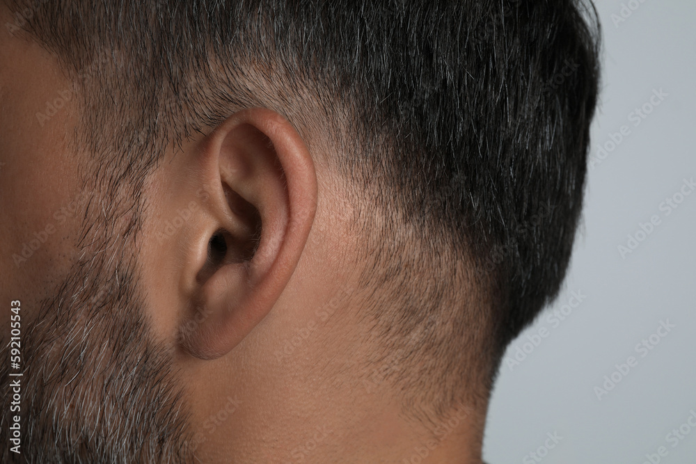 Fototapeta premium Man on light grey background, closeup of ear