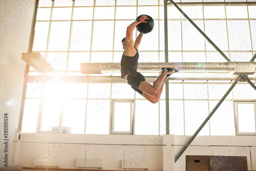 athletic guy at crossfit training jumps and throws medicine ball in the gym, strong man is doing fitness with ball